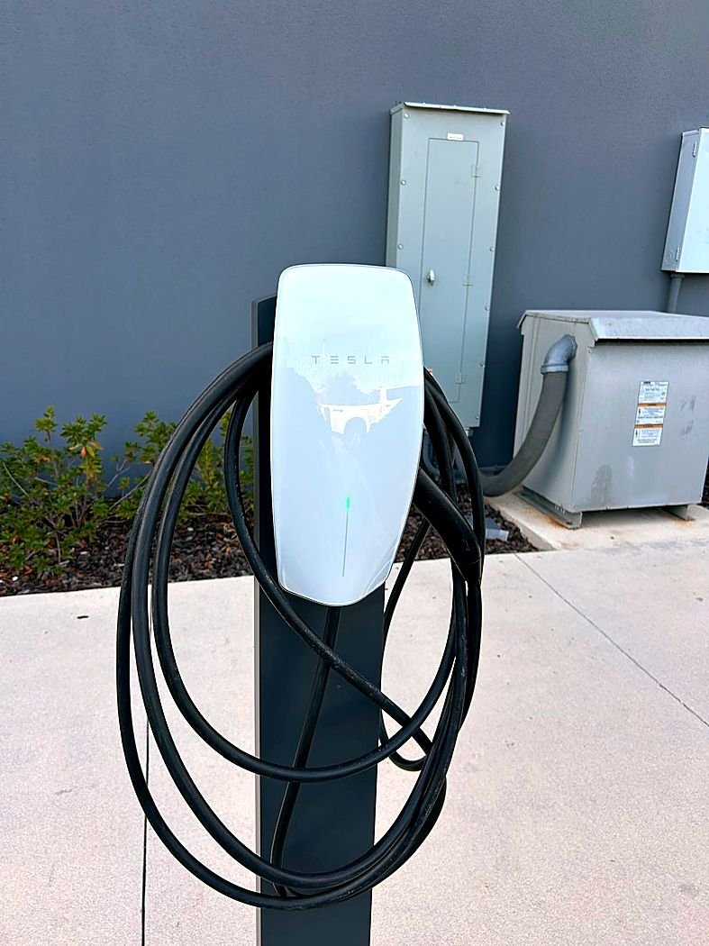 Pedestal-mounted EV charger next to a commercial panel and transformer
