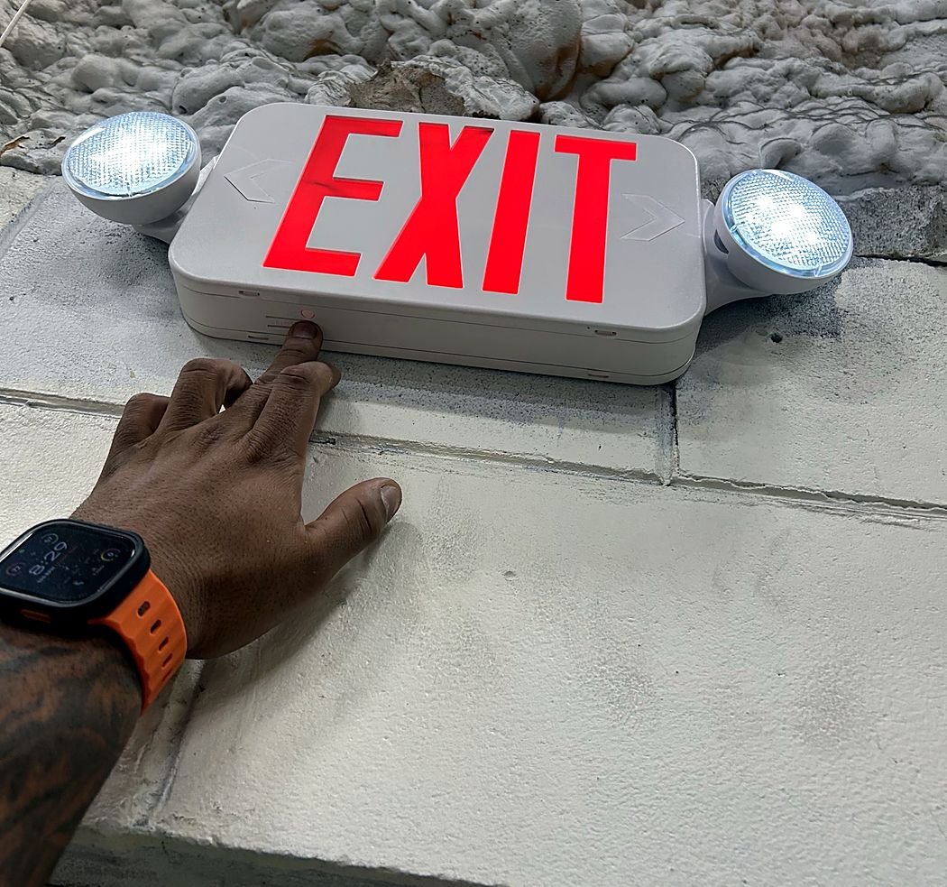 Exit sign with twin emergency heads lit during a battery test