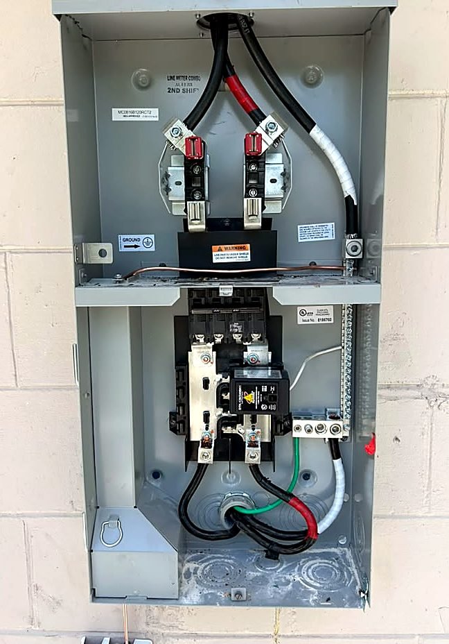 Outdoor meter-main combo panel with new main breaker and whole-home surge protector on a block wall