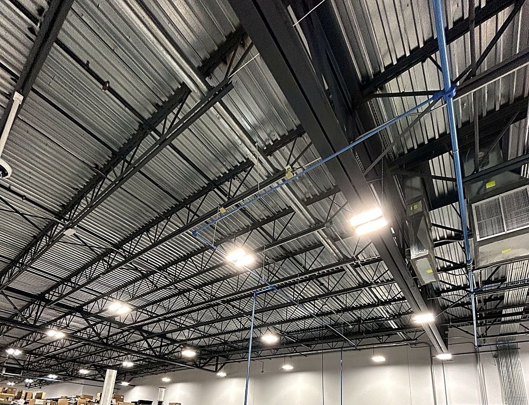 LED high-bay fixtures on an open steel ceiling in a tire shop